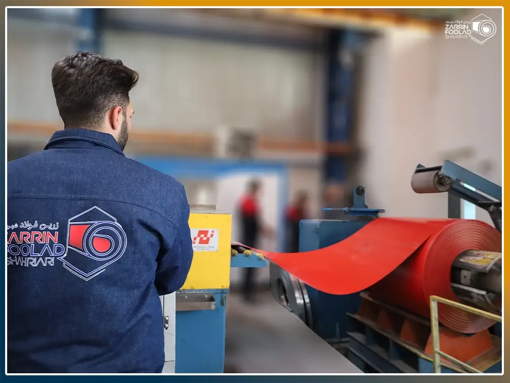 یک رول رنگی قرمز بر روی دستگاه برش است و اپراتور در حال اجرای تنظیمات دستگاه برش است.